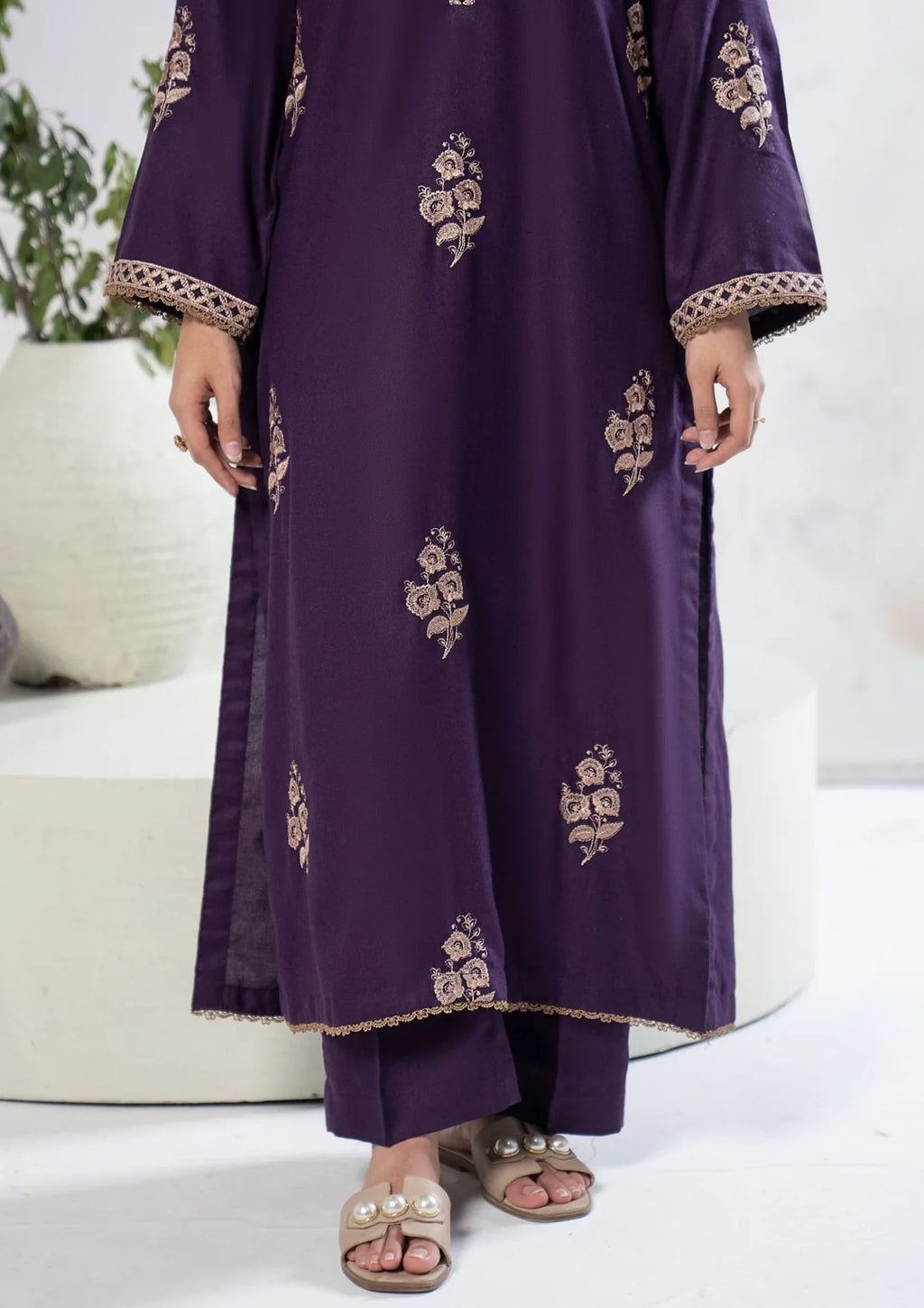 Close-up of embroidered V-neckline and floral motifs on plum shirt
