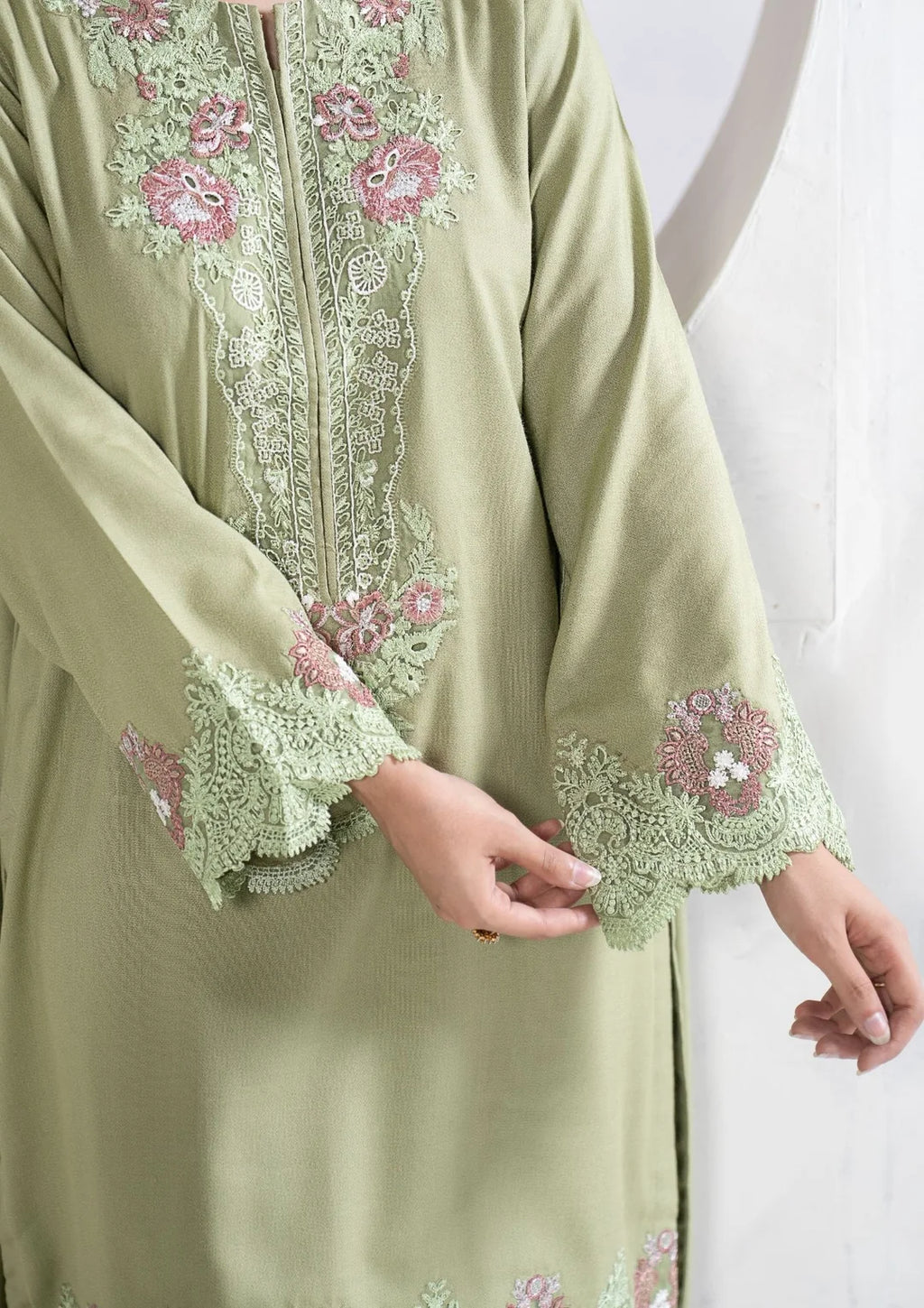 Close-up of pastel floral embroidery on green sleeve cuffs