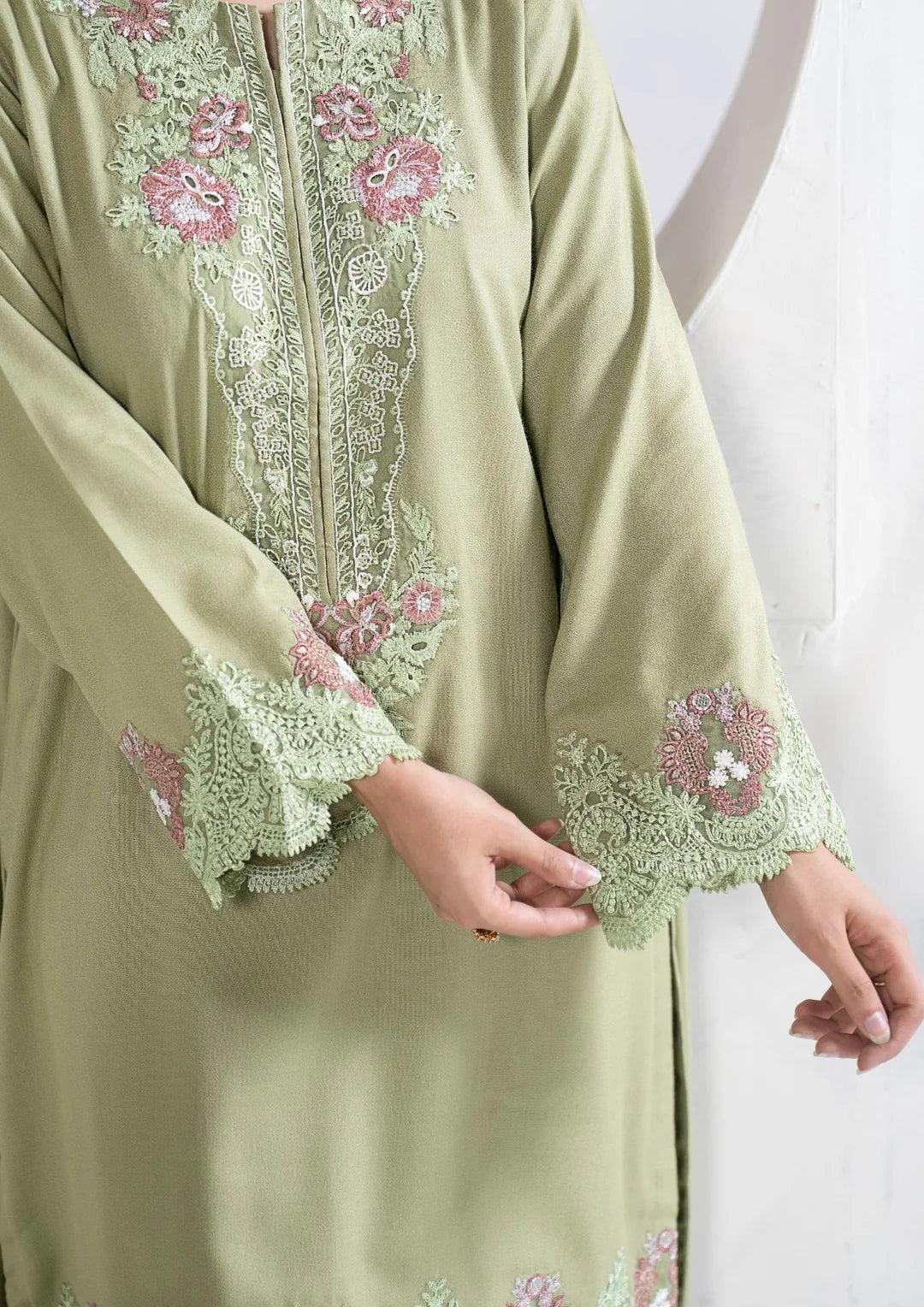 Close-up of pastel floral embroidery on green sleeve cuffs