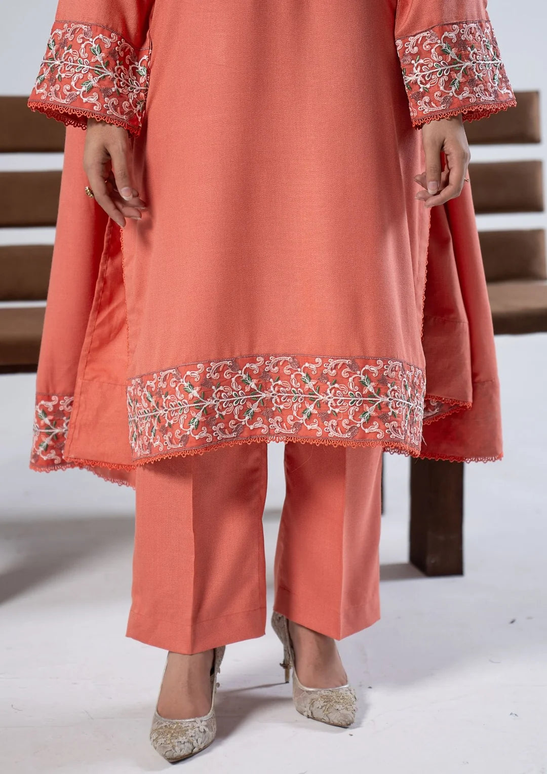 Close-up of coral shirt hem and sleeve embroidery with matching trousers