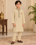 Boy wearing a beige embroidered kameez with matching pajama trousers