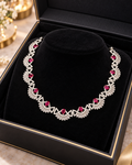 Silver-colour necklace with red stones and sparkling accents displayed in a black jewellery box